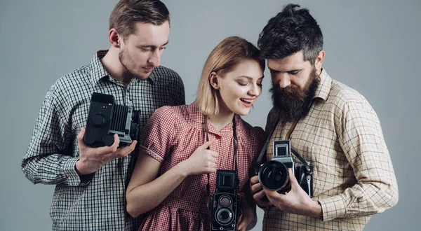 What a shot. Photography studio. Retro style woman and men hold analog photo cameras. Paparazzi or photojournalists with vintage old cameras. Group of photographers with retro cameras