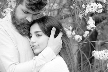 Aşık çift bahar bahçe, dalları arka plan üzerinde çiçekler ile vakit geçirmek. Çiçek Bahçe erkek ve kadın hugs bahar gününde. Çift çiçek açan ağaçlar sarılmak. Bahar Tarih kavramı.