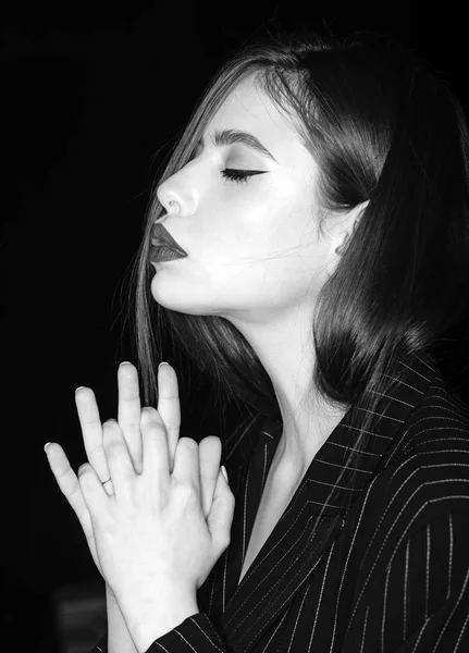 Concepto de oración y esperanza. Chica en la cara tranquila con los ojos cerrados en chaqueta negra, fondo negro. Mujer con maquillaje elegante y peinado toma de la mano como la oración, vista lateral . —  Fotos de Stock