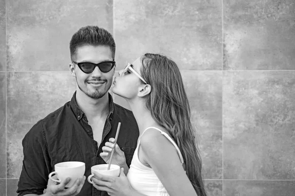 What else is there to do than kiss. Girlfriend and boyfriend have espresso drink together. Couple of woman and man with coffee cups. Couple in love drink coffee outdoor. Enjoying the best coffee date