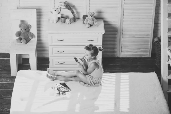Dítě namaluje rty s rtěnkou sedí v místnosti s hračkami — Stock fotografie