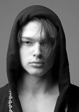 Siyah hood, gri arka planda emin yüz adam. Maço siyah bornoz ile kukuleta, yakın çekim. Erkeklik kavramı. Pürüzsüz cilt yüz ve boyun kameraya bakarak üzerinde olan adam.