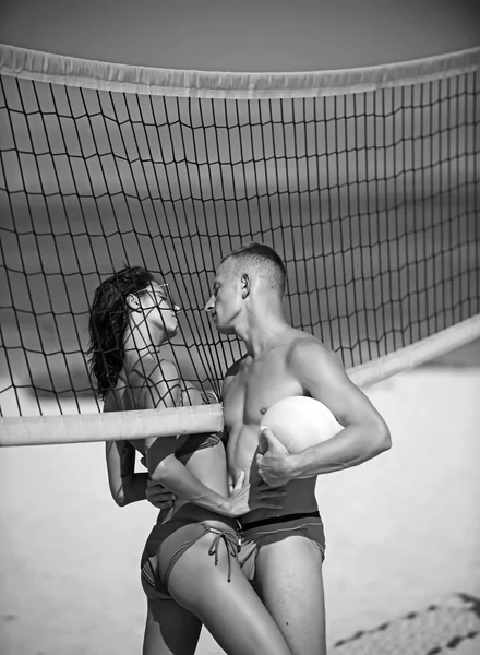Σέξι γυναίκα και μυώδης άνδρας με μπάλα στο δίχτυ. σέξι γυναίκα ή κορίτσι φλερτ με μυώδης άνδρας κρατώντας την μπάλα στο δίχτυ. — Φωτογραφία Αρχείου