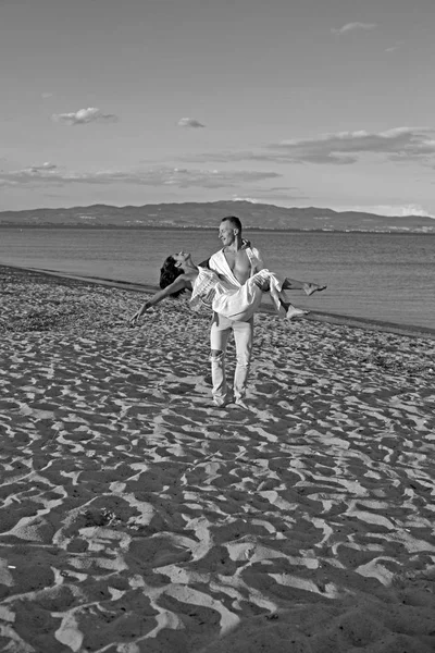 Concept de lune de miel. lune de miel de jeune beau couple avec l'homme tenant la femme sur les mains sur la plage de sable . — Photo