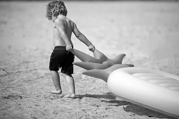 Piccolo bambino tirare materasso ad aria sulla sabbia. Vacanze estive e viaggi verso l'oceano. Materasso gonfiabile all'ananas, attività e gioia. Maldive o Miami Beach. bambino sul mare dei Caraibi alle Bahamas . — Foto Stock