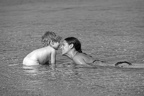 Mothers day holiday of little boy in hands of woman parent. mother with son swim in water. Happy family on Caribbean sea. Summer vacation and travel to ocean. Maldives or Miami beach activity joy.