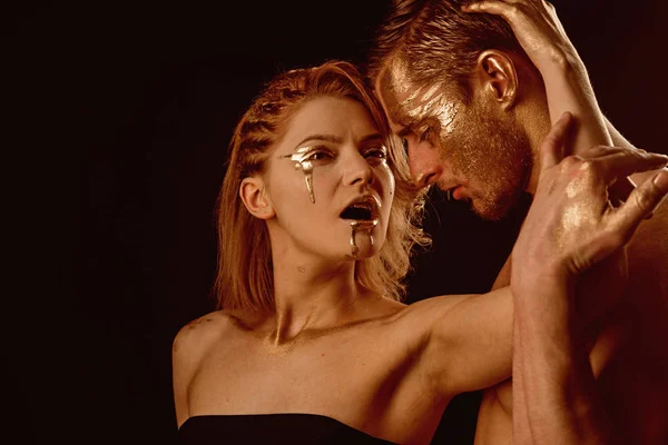 Man en vrouw betrekkingen. man en vrouw omarmen met gouden verf make-up op lichaam geïsoleerd op zwarte achtergrond, kopie ruimte. — Stockfoto