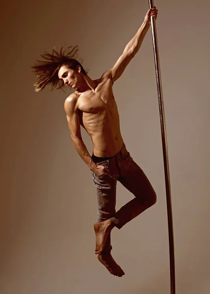 Muscular man with strong body dancing on pylon. dieting. sexy macho dancer workout on pole. Freedom. Practicing in dance studio. Pole dance sport. Athletic man make acrobatic elements on pylon.