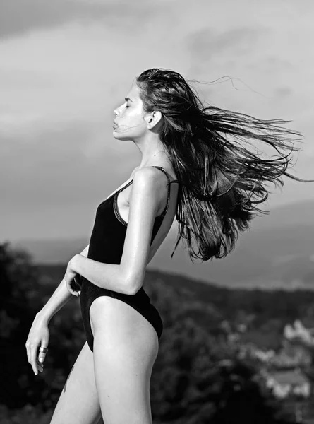 Giovane donna bruna con lunghi capelli sciolti e con figura fitness sta in un body nero — Foto Stock