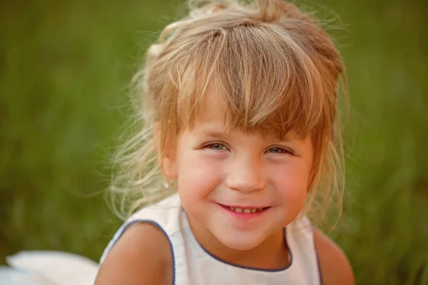 Menina com cabelo loiro sorriso na grama verde — Fotografia de Stock