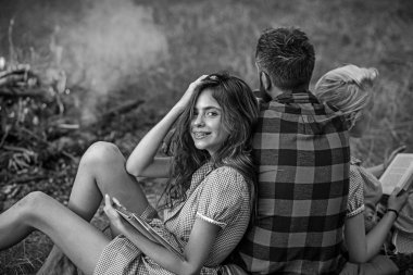 Gülümseyen esmer arkadaşı eğilerek diş teli ile. İki güzel kız kitap okurken ateş arayan adam geri dön. Gevşeme doğada, dostluk kavramı