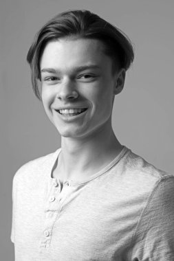 Adam mutlu yüz ışık gömlek, gri arka planda gülümseyen üzerinde. Maço şık uzun saç kesimi ile. Adam kameraya bakarak yüzündeki pürüzsüz bir cilt. Kuaför ve saç modeli kavramı.