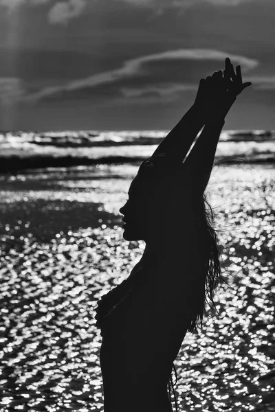 Black silhouette of pretty girl on sea beach in evening