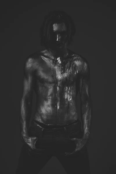 Homem com tronco nu coberto com tinta prateada, fundo escuro . — Fotografia de Stock