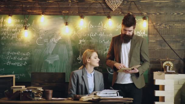 Stile vintage degli insegnanti. L'uomo barbuto legge un libro mentre una donna stampa testo su una macchina da scrivere su uno sfondo di legno in classe. Gli scrittori scrivono una sceneggiatura . — Video Stock