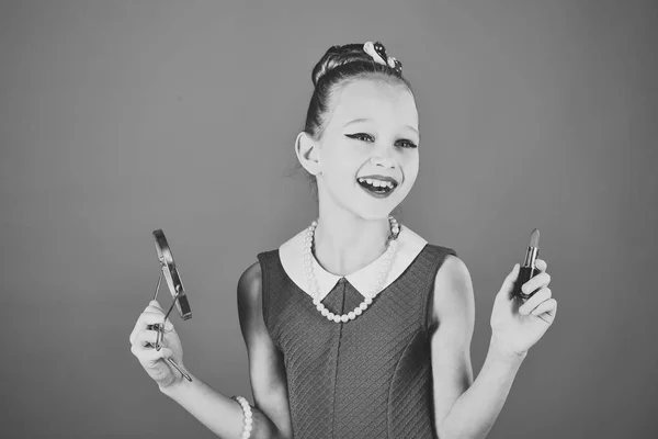 Niña sostiene lápiz labial y espejo. Chica retro, moda, cosméticos, belleza. Maquillaje y look retro, peluquero. Niña en vestido elegante, maquillaje. Moda y belleza en estilo pinup, infancia . — Foto de Stock