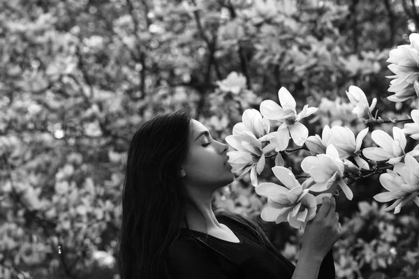 Menina adorável cheirando rosa, florescendo, flores de magnólia da árvore — Fotografia de Stock