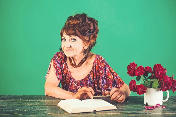 Mulher velha livro de leitura com óculos e flores — Fotografia de Stock