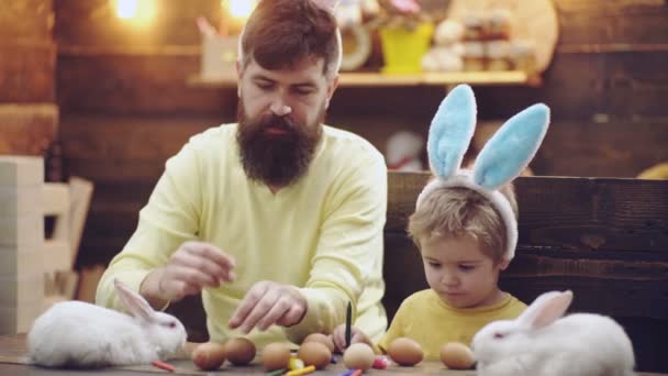 Otec a syn malovat velikonoční vajíčka. Velikonoční svátky. Šťastná rodina, příprava na Velikonoce. Veselé velikonoce. Velikonoční vajíčka. Velikonoční vajíčka na dřevěné pozadí.