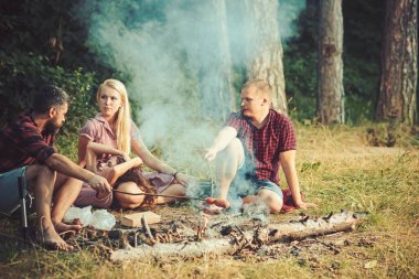 Ormanda kamp arkadaş grubu. İnsanlar eğlenmek kamp ateşi etrafında konuşuyor. Ateşte sosis pişirme