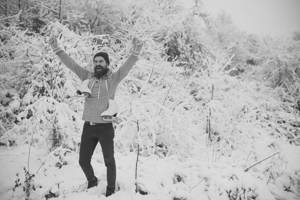 Bebaarde gelukkig man houden schaatsen in de winter van de besneeuwde bos, Kerstmis — Stockfoto