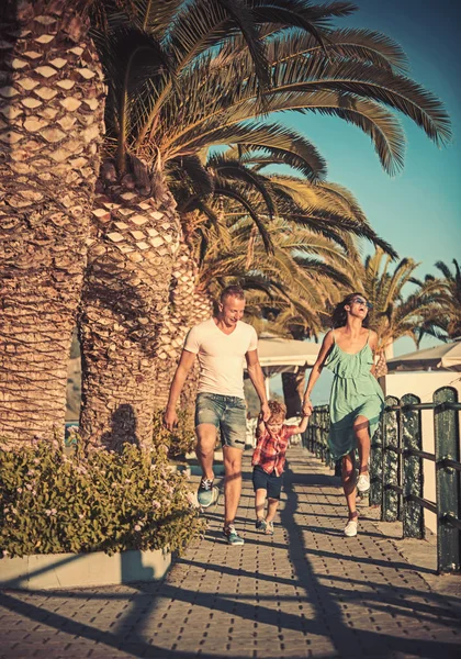 幸せな家族の夏休み。母親と息子と父親のビーチでヤシの木を歩く。父と母を持つ子。母親や父親の日に子供と家族旅行。家族の価値観としての愛と信頼 — ストック写真
