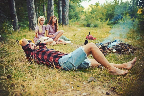 Homem barbudo em camisa lenhador deitado na grama e olhando para o céu, unidade com o conceito de natureza. Grupo de amigos acampar na floresta — Fotografia de Stock