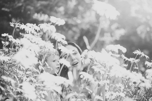 Mother and daughter on field with blossoming daisy flowers