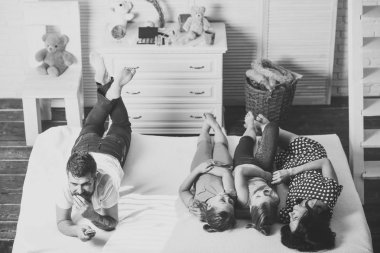 Anne, baba ve kızı yatakta yatarken uzak tv ile