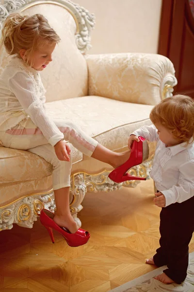 Дитячий хлопчик поклав червоне взуття на ногу сестрички — стокове фото