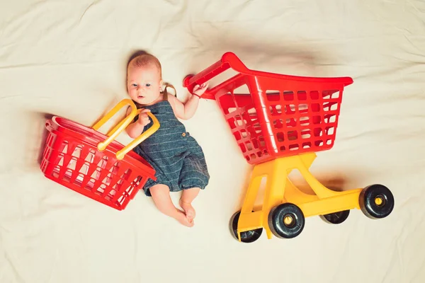 Helping mom. Childhood happiness. Big sale offer. Small girl go shopping. Sweet little baby. New life and birth. Shopping cart. Householder. Family. Child care. Portrait of happy little child