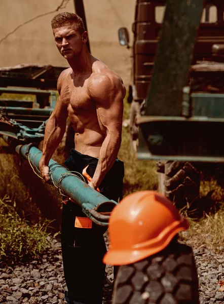Builder concept. Builder at work. Builder with muscular torso lift heavy iron equipment. Strong builder on construction site