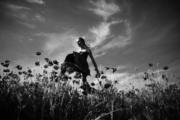 Mujer o niña posando en el campo de flores de semillas de amapola — Foto de Stock