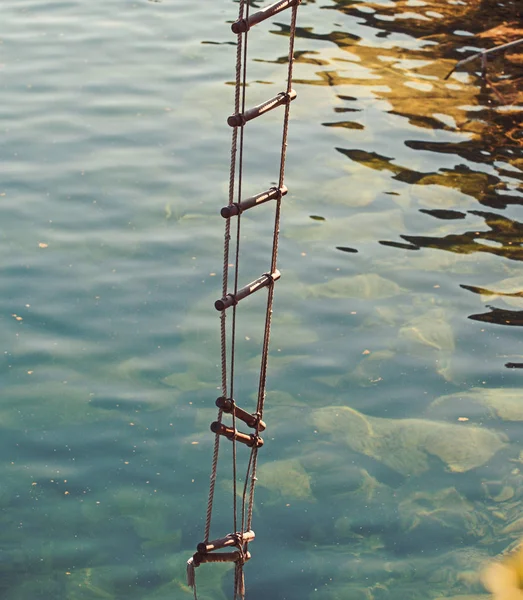 La escalera del éxito nunca se llena en la parte superior. Escalera de cuerda con escalones de madera. Cuerda sobre la superficie del agua. Rescate o cuerda de escape. Escalera Jacobs. Altura de ambición. La ambición es el camino hacia el éxito —  Fotos de Stock