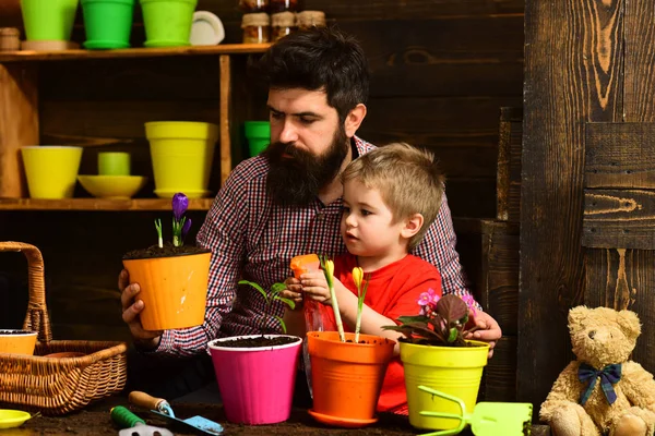 Flower watering. Soil fertilizers. Father and son. Fathers day. Family day. Greenhouse. man and little boy child love nature. happy gardeners with spring flowers. I like taking care of the flowers