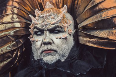Adam dikenler veya siğiller ile yüz pırıltılar ile kaplı. Şeytan siyah zemin üzerine altın yakalı. Uzaylı, iblis büyücü makyaj. Fantezi kavramı. Beyaz sakallı komuta sizde canavar gibi giyinmiş.