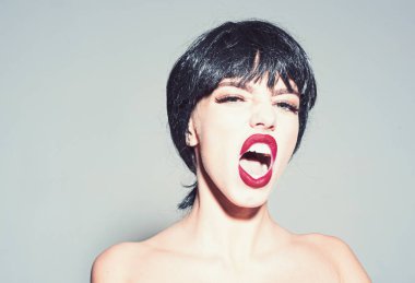 Siyah peruk Bayan gri arka plan üzerinde olun. Skandal kadın kavramı. Kadın çekici kırmızı dudaklar ile kameraya benziyor. Kız çıplak omuz ile poz skandal bağırarak yüzünde.