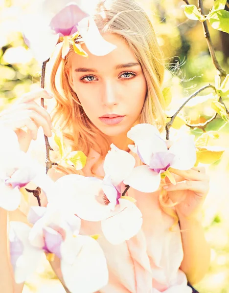 Chica en la cara de ensueño, tierna rubia cerca de magnolia flores, fondo de la naturaleza. Mujer joven disfrutar de las flores en el jardín. Concepto de primavera. Lady camina en el parque en el soleado día de primavera . — Foto de Stock
