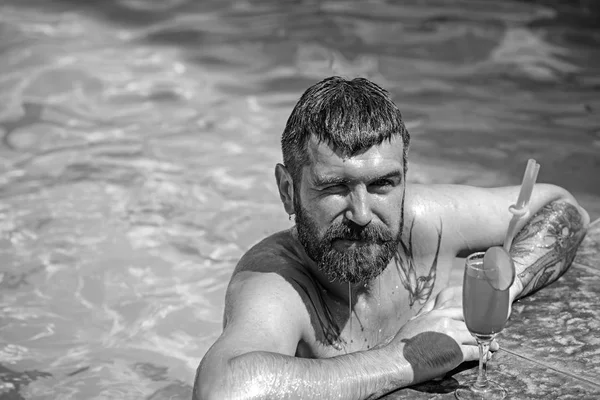 Détendez-vous en mer et station thermale. Fête de piscine avec hipster en eau bleue. L'homme nage et boit des boissons alcoolisées. Vacances d'été à Miami Beach ou aux Maldives. Cocktail avec homme barbu dans la piscine — Photo