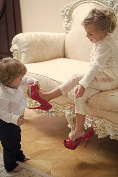 Bebé niño poner zapato rojo en la pierna de hermana niña —  Fotos de Stock