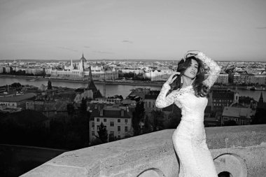 Beyaz düğün gelin kadın elbise üzerinde şehir manzaralı. Balkonda uzun saçlı gelin.