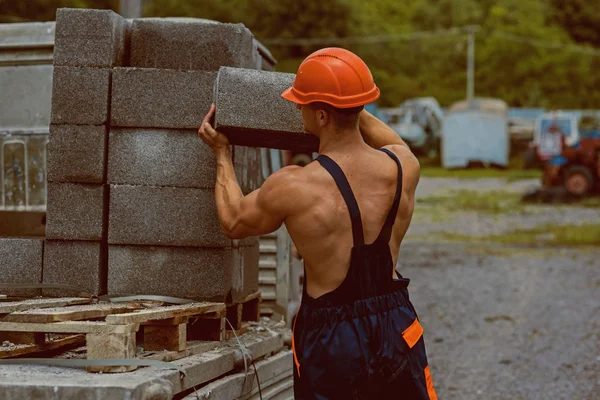Construction worker. Construction worker carry bricks. Construction worker unload truck. Construction worker in working uniform. Building tomorrow world today