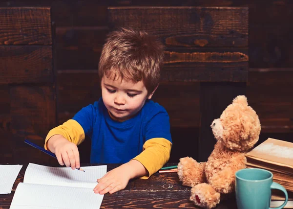 Un ragazzino che scrive nei libri di testo. Un ragazzo diligente che impara le lettere. Concetto di apprendimento precoce — Foto Stock