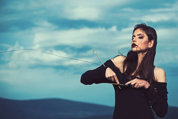 Knitting, fashion makeup and hairstyle of woman. knitting black dress on young woman on blue sky background, copy space