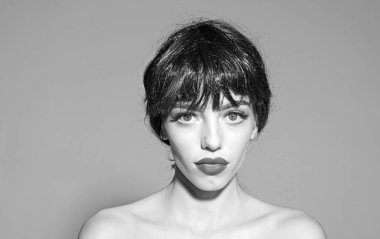 Siyah peruk Bayan gri arka plan üzerinde olun. Makyaj ve visage kavramı. Çekici dudaklar kadınla kameraya benziyor. Kız çıplak omuz ile poz sakin dalgın yüzünde.