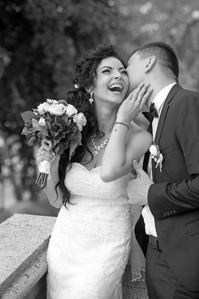 女と男は、結婚式の日に笑顔します。新郎は花束と幸せな花嫁をキス。恋の結婚式。夏の屋外の新婚カップルします。結婚の概念。愛と家族 — ストック写真