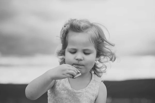 Menina criança comer biscoito no dia de verão no céu nublado — Fotografia de Stock