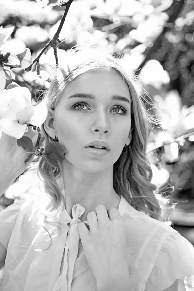 Chica en la cara de ensueño, tierna rubia cerca de magnolia flores, fondo de la naturaleza. Lady camina en el parque el soleado día de primavera. Concepto de primavera. Mujer joven disfrutar de flores en el jardín . — Foto de Stock