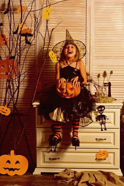 Happy little girl with halloween pumpkin. Wicked little witch. Girl happy smiling on halloween. Prettiest pumpkin in the patch. Happy halloween to all