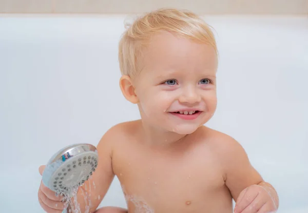 Miúdo sorridente na casa de banho com pato de brinquedo. Bebê sorridente tomando banho sob um chuveiro em casa. Pequena criança banho em sabonetes . — Fotografia de Stock